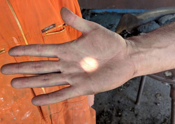 A dot of light is caught on the palm of an open hand