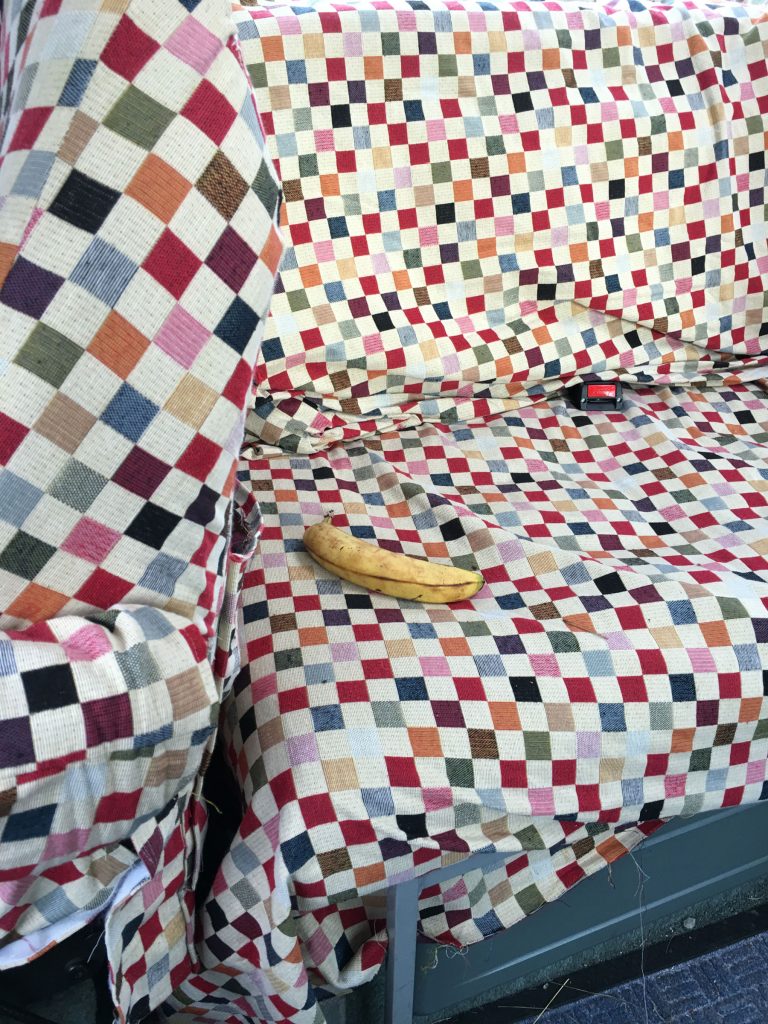 a banana sits on a coloured chequerboard cover on a camper van sofa