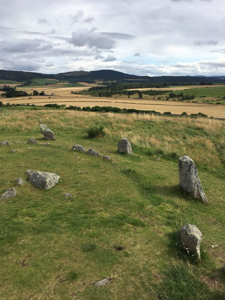 a standing stone circle with the landscape rolling out in the background