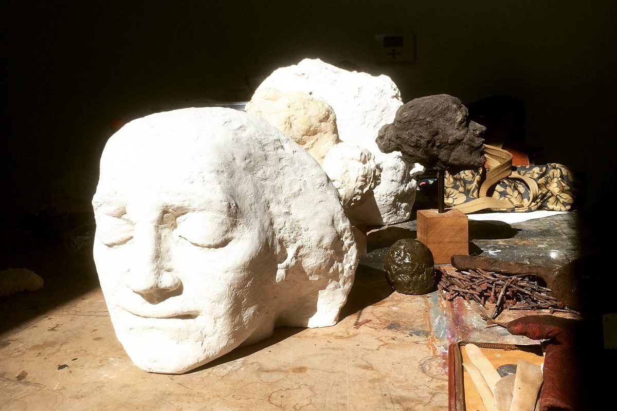 A plaster head bathes in sunlight with tools surrounding it.