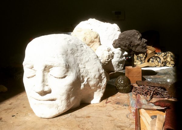 A plaster head bathes in sunlight with tools surrounding it.