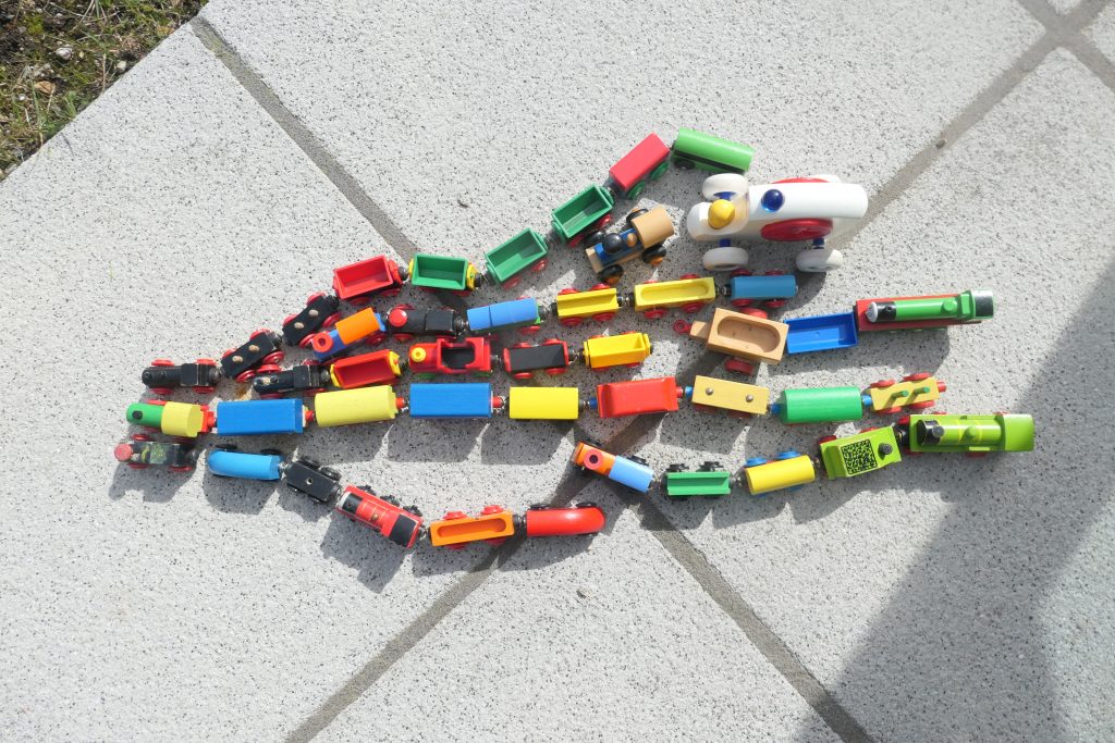 colourful toy trains and carriages branch out from one another on outdoor paving
