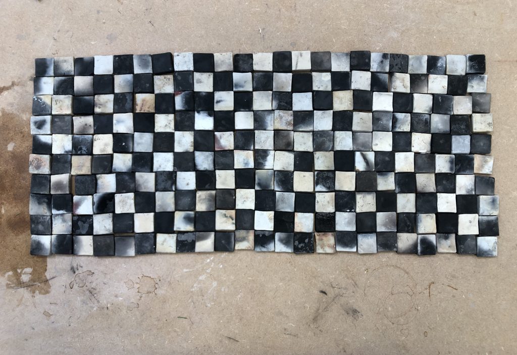 a mosaic grid of black and smoky whitish tiles